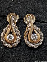 Front close-up showing the twisted rope design, gold tone accent, and clear stone on the pair of silver earrings.