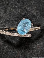 Close-up photo of the sterling silver ring showing the oval blue topaz and small clear stones on band.