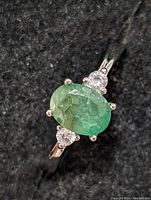 Close-up of oval emerald and clear side stones on sterling silver ring.