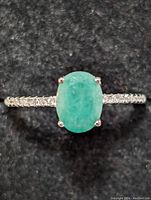 Close-up image of the sterling silver ring with oval emerald gemstone centered on thin band showing gemstone details and prong setting.