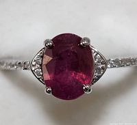 Close-up of the oval ruby set in sterling silver with clear accent stones along the band.