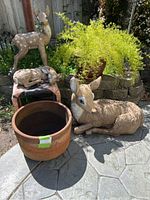 Overall view of the lot showing three deer statues and one terracotta pot on a patio.