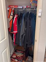Closet view showing multiple men's jackets and jerseys including a red San Francisco 49ers jersey and black leather jacket. Boxes of board games like Yahtzee and Monopoly visible on the floor.
