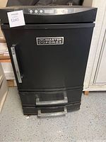 Front view of the Master Forge smoker showing the black unit, handle, and logo.