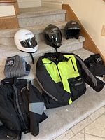 Overview of three helmets, two jackets and pants on stairs