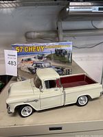 Assembled cream-colored 1957 Chevy pickup model with red bed, chrome details visible, placed in front of the sealed kit box.