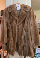 Front view of the brown fur coat with large lapels and leather belt hanging on hanger.