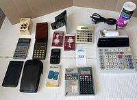 Full view of lot showing calculators and accessories laid on white surface