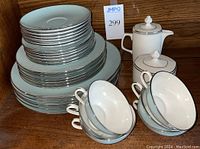 Stacked dinner plates, salad plates, bowls, and teacups with creamer and sugar bowl on the side.