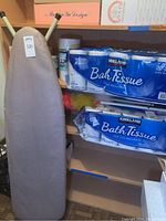 Ironing board and large packs of Kirkland bath tissue on shelves
