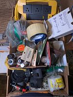 Box containing extension cords, adhesive tape, small hardware parts, small bottles and miscellaneous supplies packaged loosely.