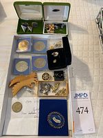 Full overview of the lot with cufflinks, coins, wooden eagle pin, assorted metal pins in box, and blue felt Anaheim pin.