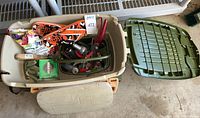 Main top-down view of the plastic Suncast cart showing included items inside, including garden shears, prune shears, gloves, kneeling pad, flip flops, and plant food bags.