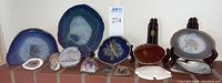 Overview of all items on brick surface showing two large agate slices, geode clock, smaller geode halves, sand dollar, shell