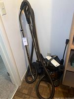 Full view of the Rainbow SE canister vacuum cleaner with metal wand and flexible hose resting against a wall.