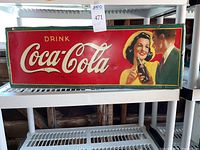 Front view of metal Coca-Cola sign with 'Drink Coca-Cola' text and illustration of couple