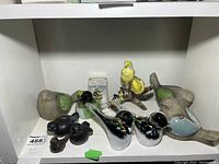 Overview of all bird figurines on a white shelf showing variety of glass and ceramic birds with various colors and sizes.