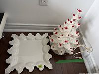 Photo showing both ceramic items: the decorative light-up Christmas tree and the square snowflake motif serving plate.