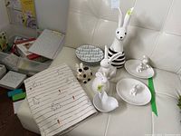 Full lot displayed on white couch showing all ceramic bunny plates, figurines, placemats, chick candy dish, and other items
