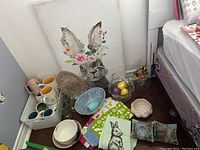 Wide photo showing the complete lot including bunny art print, mugs, bowls, glasses, tea towels, and candy dishes with Easter eggs