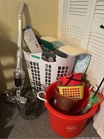 Photo of white laundry hamper, Electrolux vacuum, red bucket, wire baskets, static duster, and spa mat to show all lot items
