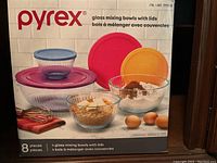 Front view of Pyrex box showing 4 glass mixing bowls with colored lids in use, demonstrating sizes and usage for food mixing and storage.