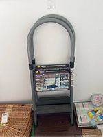 Single folded Cosco metal two-step stepladder showing front with label on step surface.