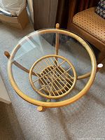 Top view of round rattan coffee table with glass top showing woven rattan details under glass.