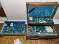 Overall view of jewelry box with hinged lift tray opened and one drawer also shown alongside, containing costume jewelry.