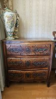 Front view of dresser showing three carved drawers and brass hardware