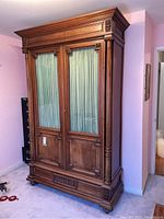 Full front view of the armoire showing two-door design, carved base and cabriole legs.