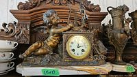 Full front view of mantel clock showing cherub figure on marble base with metal details.