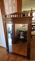 Full view of the antique mirror showing the wooden frame and reflective glass.