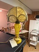 Full view of the vintage boudoir lamp showing yellow glass base and shell shade linked with metal fasteners.