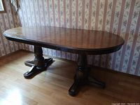 Photo of the wood dining table showing the two pedestal legs and overall shape including the leaf detached and leaned against the wall.