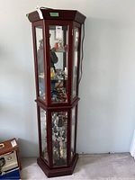 Front view of tall wood display cabinet with glass doors showing interior shelves and mirrored back.