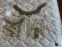Overview of mixed jewelry items on mattress and trays
