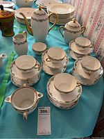 Photo showing full tea set with teapot, multiple teacups with saucers, covered canister and pitcher on blue tablecloth.