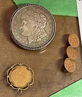 All three pieces displayed together: Morgan brooch, French coin pendant, three-coin lapel pin
