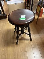 Top view of round wooden seat of vintage piano stool, showing the wood grain and finish.