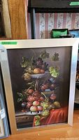 Full view of the original still-life painting on canvas framed, featuring fruit and leaves on a table with a draped red cloth.