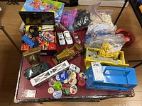 Overview photo showing assorted vintage LEGO bricks, pins, die cast cars, model car clock, and thermos lunch pail