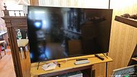 Front view of the Vizio 55 inch TV on wooden table with remotes placed in front.