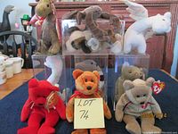 Ten assorted Beanie Babies displayed, four in clear protective cases on a blue cloth, showing size and condition