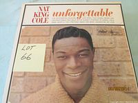 Close-up of Nat King Cole album cover 'Unforgettable' with smiling portrait of the artist and list of tracks.