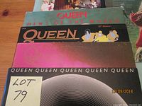 Four albums stacked showing Queen albums and others
