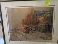 Framed winter streetcar scene print showing red streetcar on snowy tracks in front of red brick buildings in Toronto.