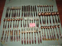 Overview of all 72 flatware pieces arranged on cloth to show full set.
