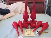 Two red Danish drop wax candles placed in their matching holders with other four loose red Danish drop wax candles arranged around.