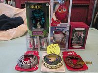 Photo showing various Christmas ornaments on table including Incredible Hulk ornament, Furby and Angry Birds boxed ornaments, and other decorative holiday items.